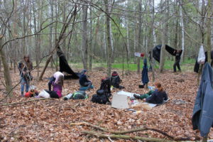 Ein Nachtlager in einem Laubwald wird von einigen Pfadfinderinnen aufgebaut.