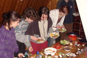 Fünf Pfadfinder und Pfadfinderinnen stehen vor einem Buffet, und legen Essen auf ihre Teller.