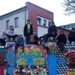 Die Gruppenmitglieder der Sippe Azules sitzen auf einer Graffitibemalten Mauer und posen für das Gruppenbild.