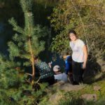 Mehrere Kinder sitzen am Hang eines Steinbruchs. Ein Kind steht gerade auf, sieht in die Kamera und kneift die Augen zu da die Sonne ihr ins Gesich scheint.