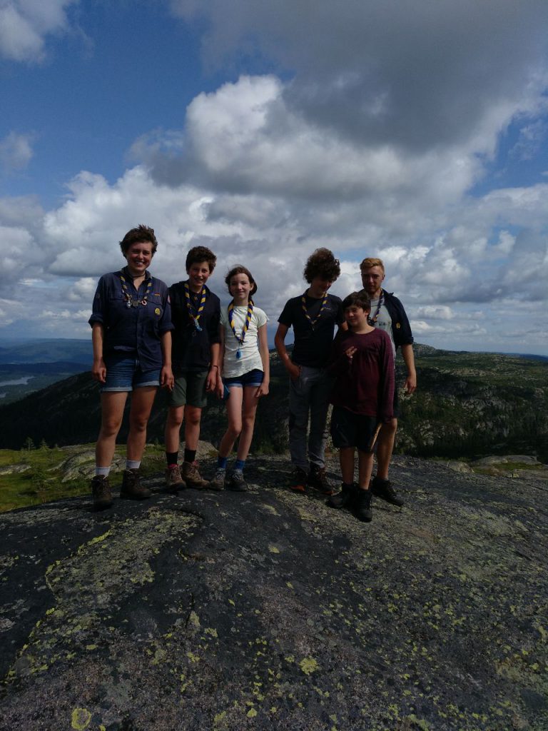 Die Pfadis stehen auf einem Fels, im Hintergrund sieht man eine weite Aussicht über die bergige Landschaft Norwegens.
